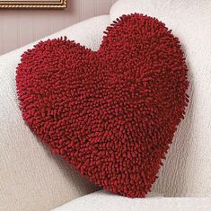 a red heart shaped pillow sitting on top of a white couch