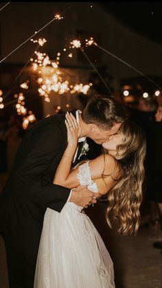 a bride and groom kissing in front of fireworks