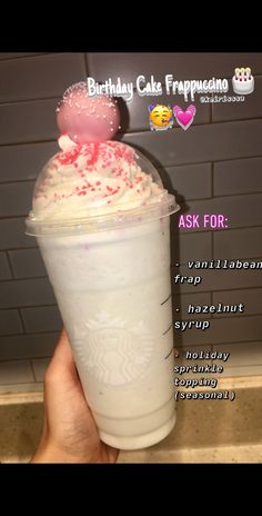 someone holding up a birthday cake frappuccino milkshake with whipped cream and sprinkles