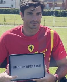 a man in a red shirt holding up a sign that says smooth operator on it