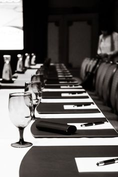 a long table is set up with wine glasses and pens