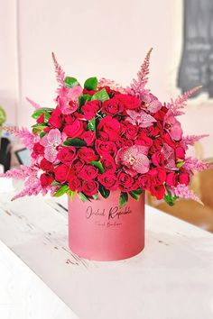 a pink vase filled with lots of red flowers