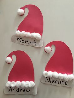 three santa hats made out of paper with name tags attached to the back of them