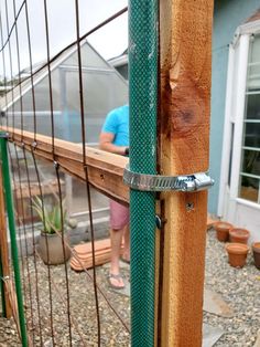 a person standing next to a wooden fence with a green metal bar on it's side