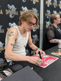 a young man signing autographs for fans at a comic convention in california, usa