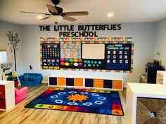 a classroom with colorful rugs, chairs and a large bulletin board on the wall