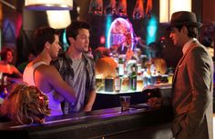 three men standing at a bar talking to each other