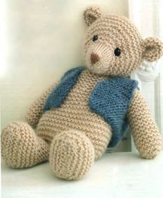 a crocheted teddy bear with a blue vest