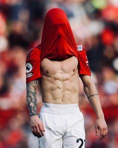 a shirtless soccer player is walking on the field with his head covered in a red hoodie