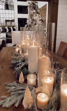 a table topped with lots of candles next to a christmas tree