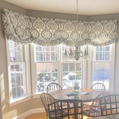 a dining room table with four chairs next to a window