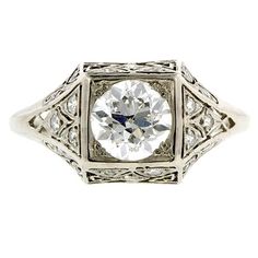 an antique style diamond ring with filigrees on the sides and a center stone