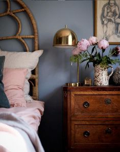 a bed room with a neatly made bed and flowers on the night stand next to it