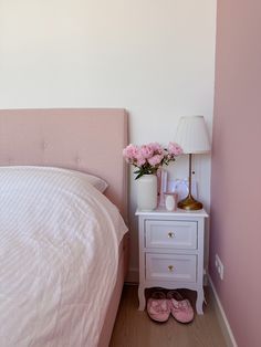 a bedroom with a bed, nightstand and flowers on the night stand in front of it