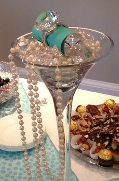 a table topped with a martini glass filled with candy and other desserts on top of it