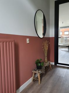 an empty room with a mirror and plant on the floor next to a wooden bench