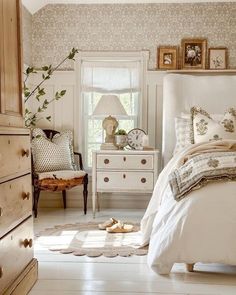 a white bed sitting in a bedroom next to a dresser and window with pictures on it