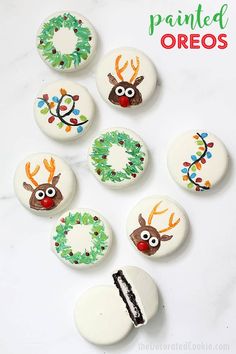 painted oreos with reindeer faces and wreaths on them, sitting next to a piece of cake