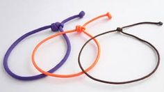 two different colored bracelets on a white surface with one purple and the other orange