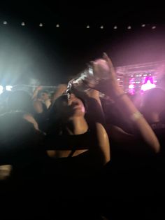 a woman holding up her cell phone in the air at a concert