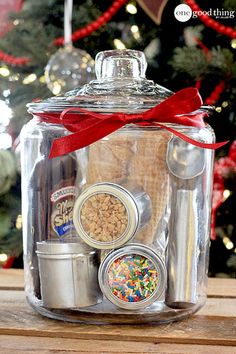 a glass jar filled with confetti and spices next to a decorated christmas tree