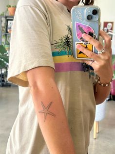 a woman with a starfish tattoo on her arm taking a selfie in the mirror