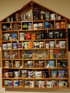 a wooden shelf filled with lots of different types of coffee cups and mugs on it