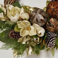 a christmas wreath with pine cones, flowers and other holiday decorations on top of it