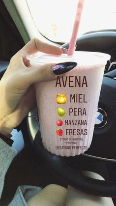 a woman holding a drink in her hand while sitting in the driver's seat