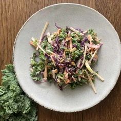 a white plate topped with salad on top of a wooden table