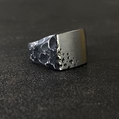 Black Zirconium Meteor Shower Ring. Designed and carved to look like it was forged through an intense Meteor shower. Black Zirconium is the only metal that can be treated to turn black and the most durable option when it comes to creating a black ring. This ring is hand-carved from a solid block of metal. Clients have various options in terms of width and finger size. Clients also have the opportunity to either have the top black or silver in color. Manufacturing time of these rings can take up Unique Black Stainless Steel Jewelry, Unique Black Engraved Ring, Modern Black Engraved Rings, Unique Black Engraved Signet Ring, Black Brutalist Jewelry As A Gift, Minimalist Engraved Black Signet Ring, Black Titanium Jewelry With Polished Finish, Black Brutalist Sterling Silver Jewelry, Minimalist Hand Forged Black Rings