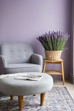 a living room with purple walls and a gray chair in the corner next to a round ottoman