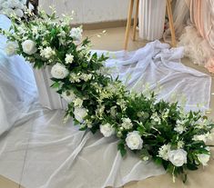 white flowers and greenery are laid out on the floor