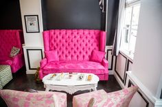 a living room filled with pink couches and chairs next to a white coffee table