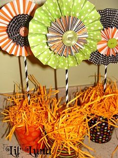 there are three pinwheels on sticks in the center of this table with straw