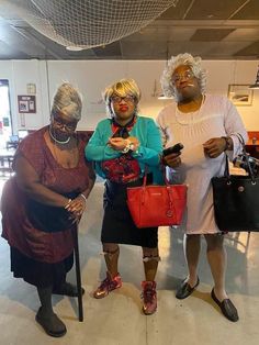 three women standing next to each other holding purses and cell phones in their hands