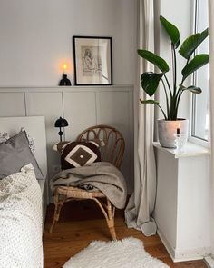 a bedroom with a chair, potted plant and pictures on the wall