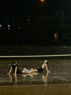 two people laying on the ground in the rain