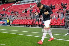 soccer player walking on the field with his hands clasped to his chest during a game