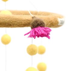 a close up of a pink flower on a branch with balls hanging from the branches