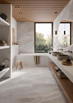 a large bathroom with two sinks and a bathtub next to a window that looks out onto the trees outside