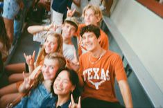 a group of young people sitting next to each other at a baseball game with their hands in the air