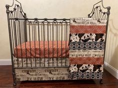 a baby crib with an orange and black blanket next to it