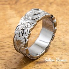 a silver ring with an intricate design on the inside is sitting on a wooden surface