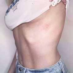 a woman with a small heart tattoo on her stomach