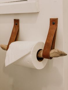 two toilet paper rolls are hanging on the wall next to a pair of wooden handles