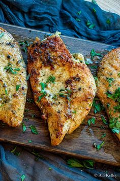 three pieces of pizza on a wooden cutting board with parmesan cheese and herbs