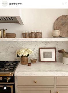 a stove top oven sitting inside of a kitchen next to a wall mounted shelf with pictures on it