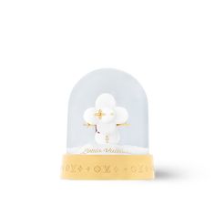 a snow globe with a white flower in it on a yellow base and gold lettering