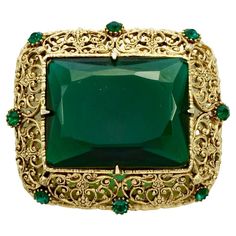 Gold plated filigree brooch featuring a large emerald green glass stone and eight green accent stones. Measuring length 5.4 cm / 2.1 inches by width 4.7 cm / 1.8 inch. This is a beautiful and elegant statement brooch with emerald green glass stones. Circa 1960s. Green Accents, Emerald Green, Green Glass, 1960s, Emerald, Gold Plate, Plating, Stone, Green